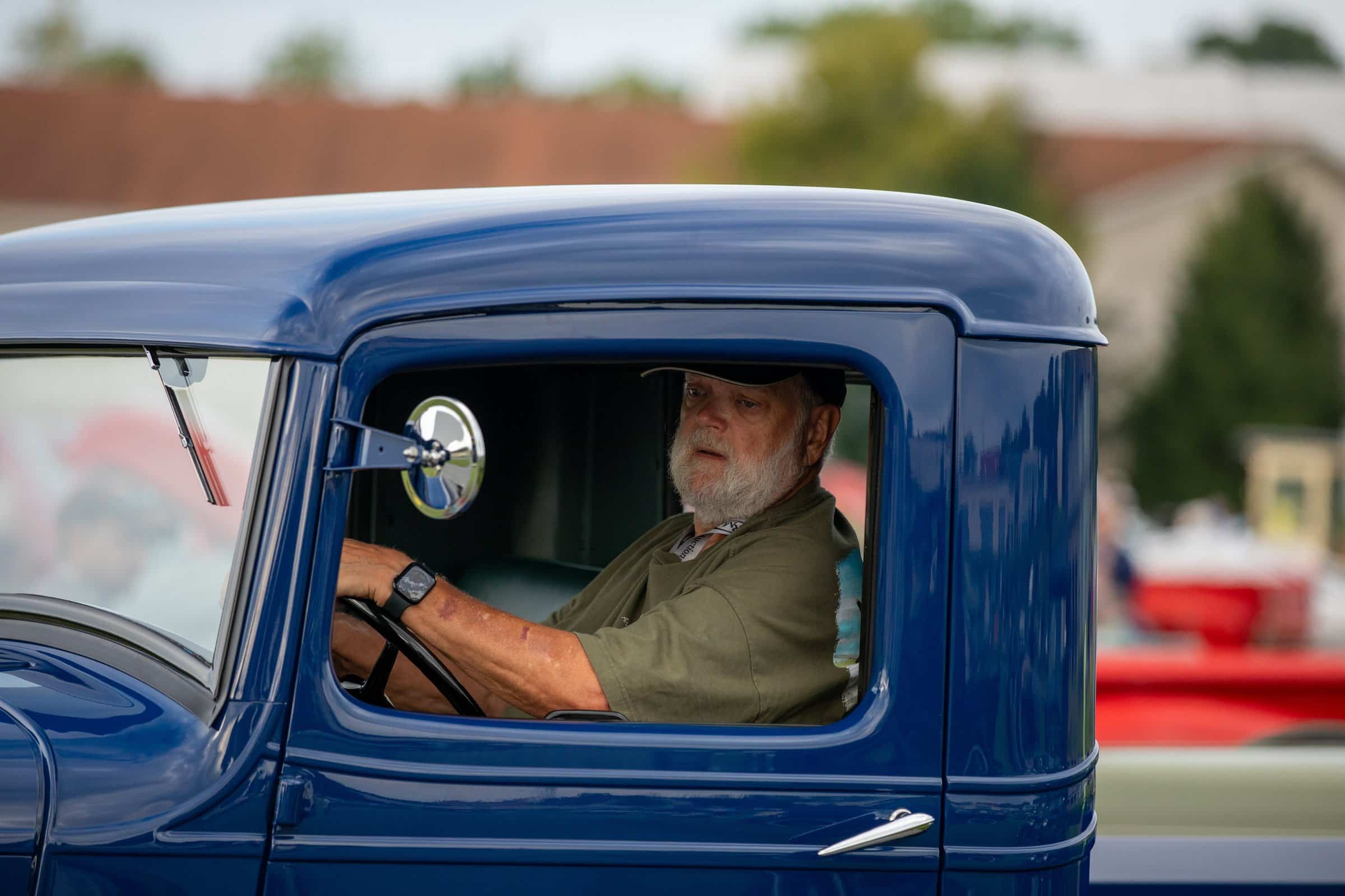 Owner framed in the cab window of a blue Ford pickup
